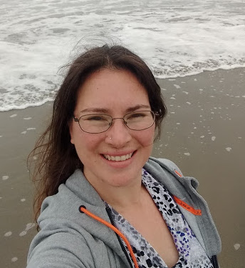 Headshot photograph of a woman at the beach.  About Me Rachel.