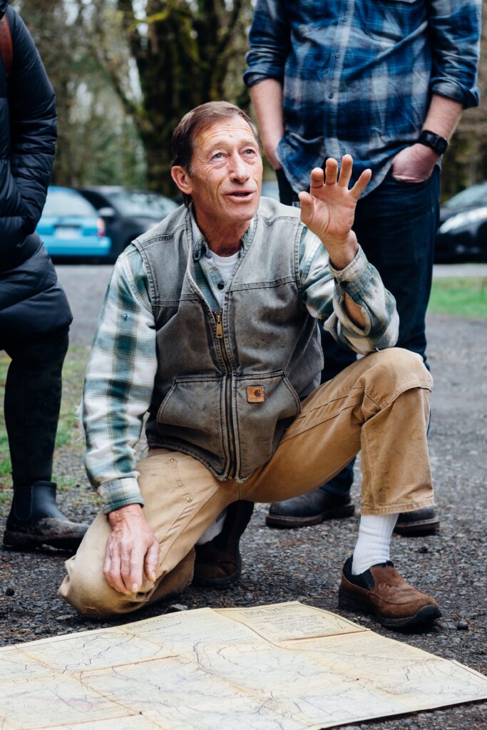 a man kneeling next to a map while talking 