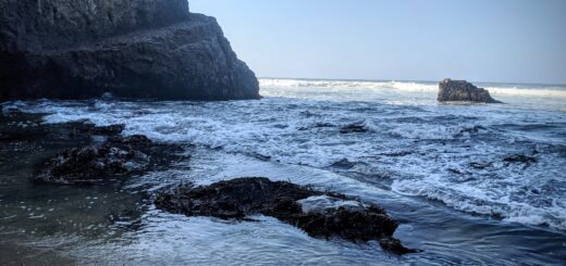 rocky cliff, beach, and waves in shdows